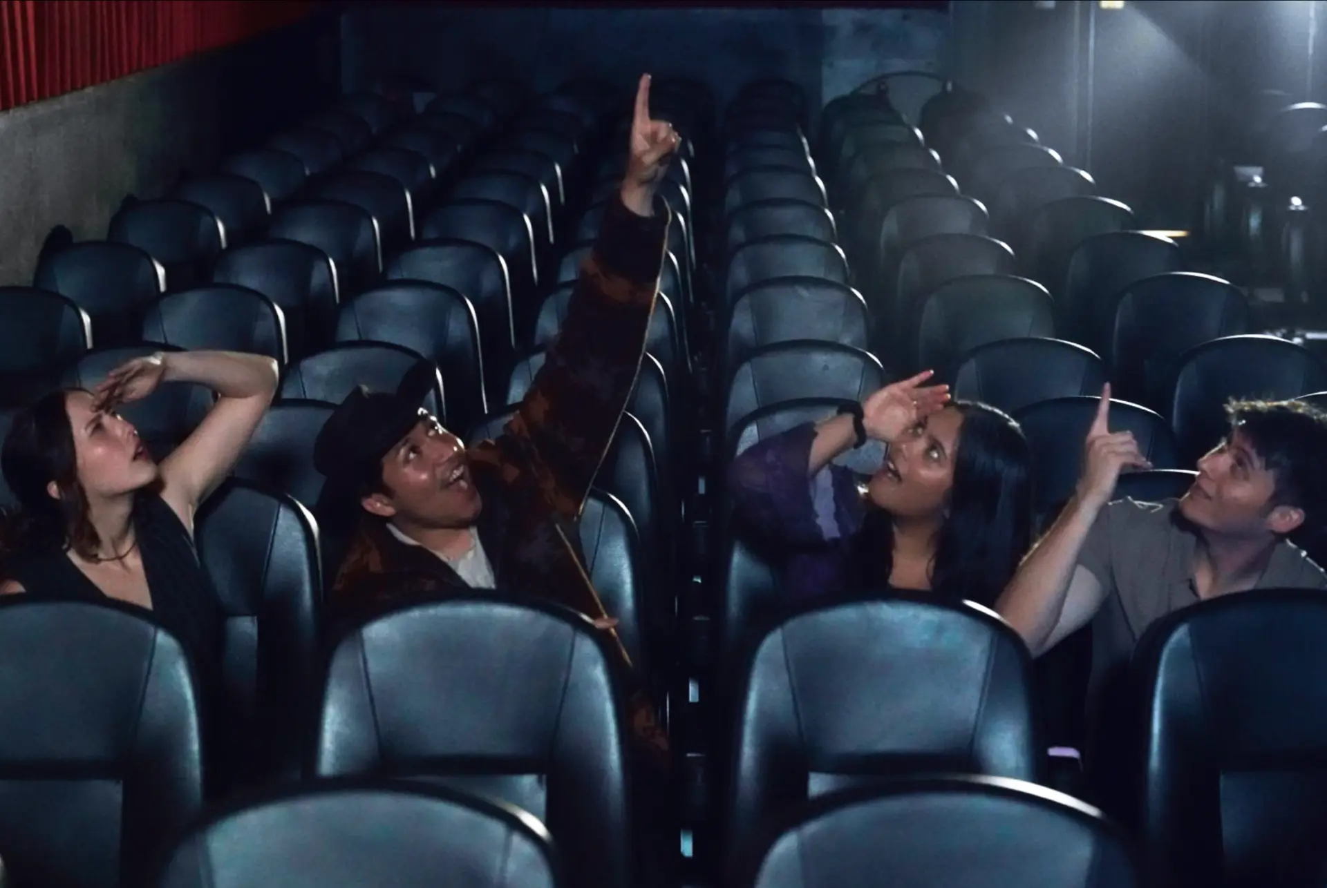 The four creators of Screen Out Loud looking up together in an empty theater auditorium
